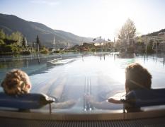 Waldhof Fuschlsee Resort Zwei Gäste liegen im Aussenpool mit Blick auf die Umgebung im Waldhof Fuschlsee Resort