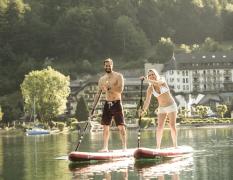 Waldhof Fuschlsee Resort Zwei Gäste beim Standup-Paddling auf dem Fuschlsee vor dem Waldhof Fuschlsee Resort
