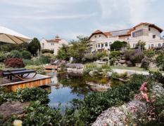 Hotel Bergergut Aussenansicht mit Badeteich und Liegen im Vordergrund des Hotels Bergergut