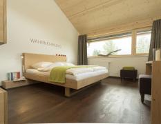 Hotel Fischer am See Modernes Doppelzimmer mit dem Schriftzug "Wahrnehmung" über dem Bett im Hotel Fischer am See ****