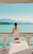 Eine Dame steht im Massagepavillon mit direktem Blick auf den See im Werzer´s Hotel Resort Pörtschach